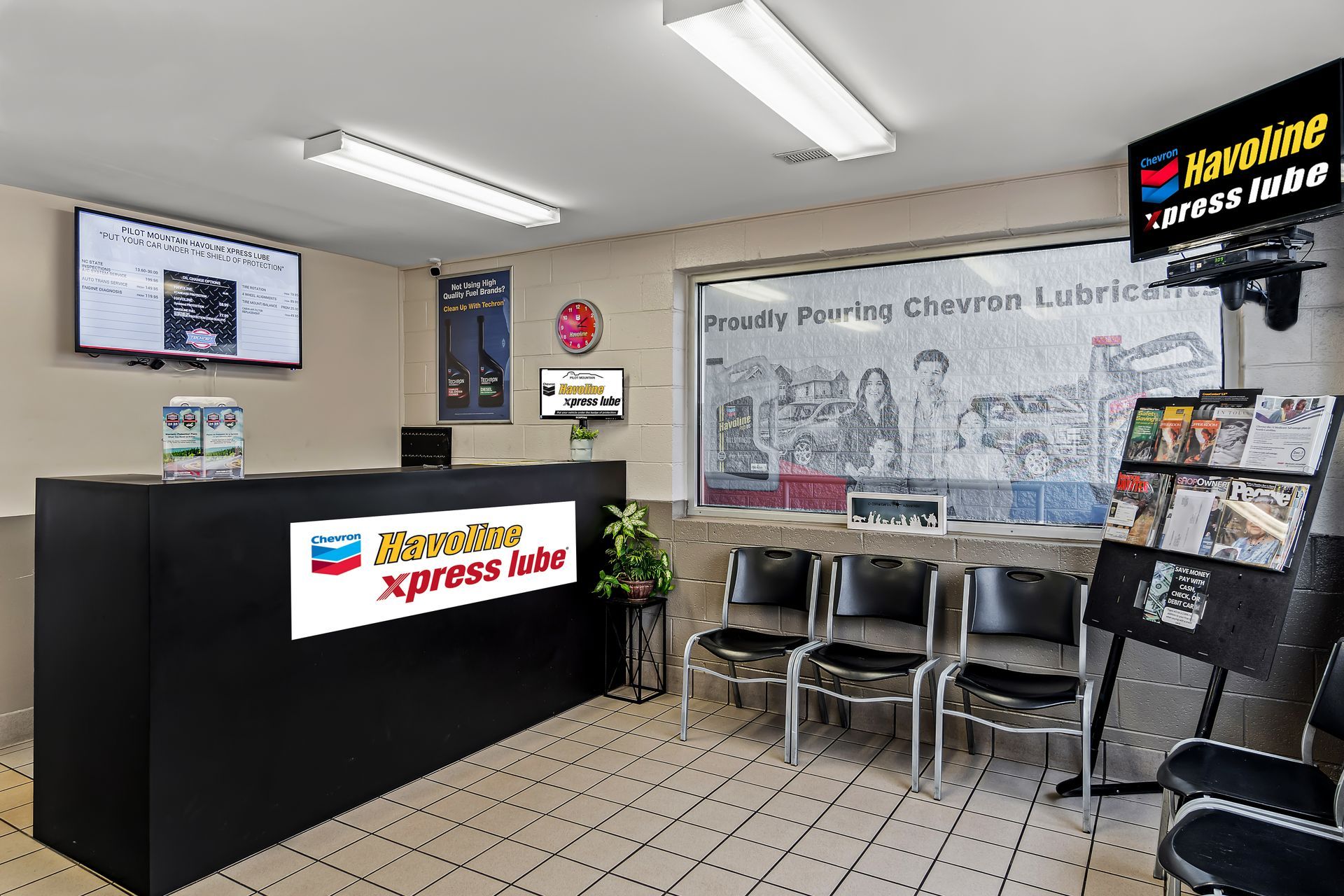 Small lobby of a library or office with reception desk, chairs, bulletin board, and mural on the wall.