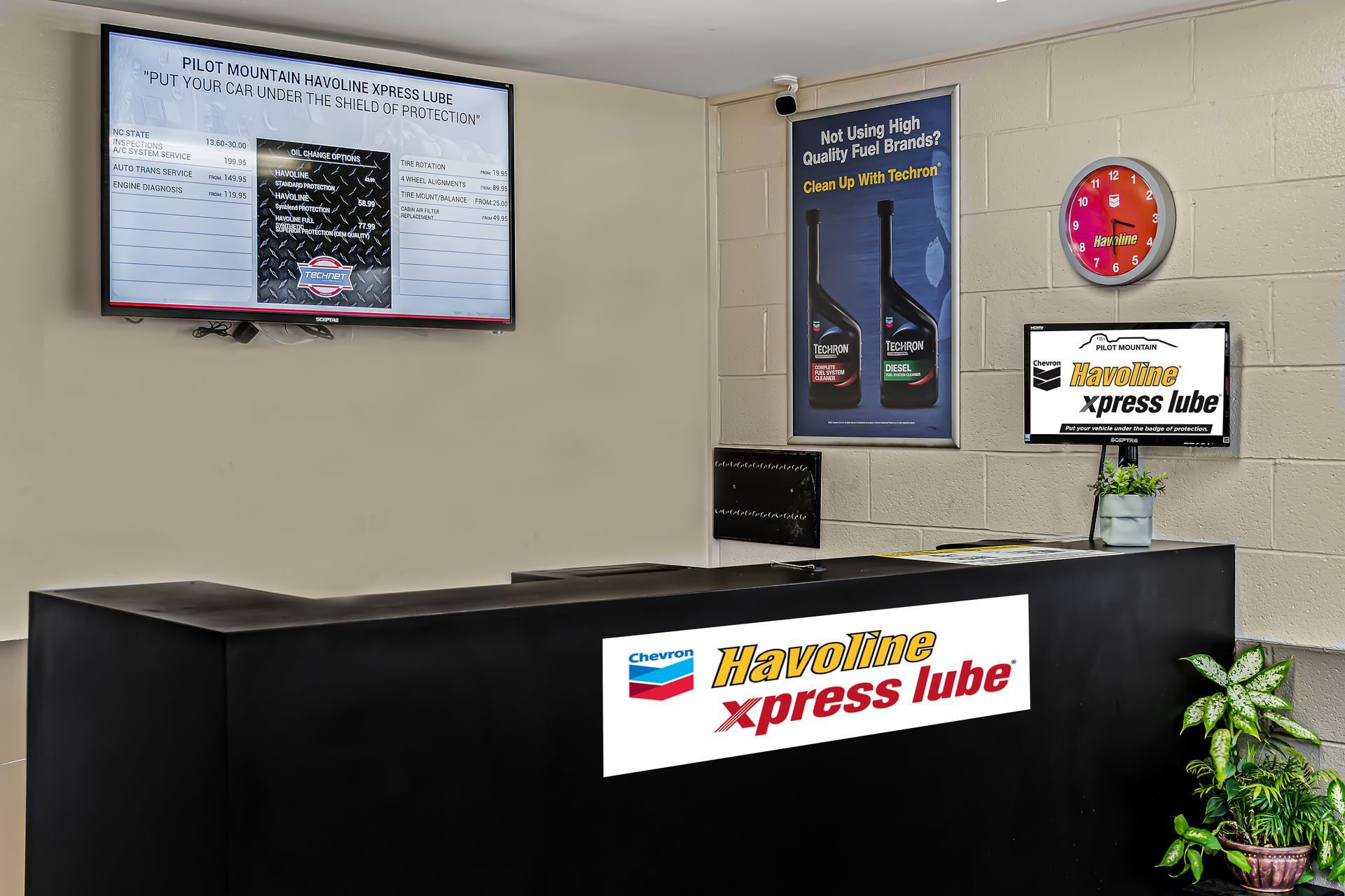 Handicapped Xpress Hub reception desk with wall signs, clock, and potted plant