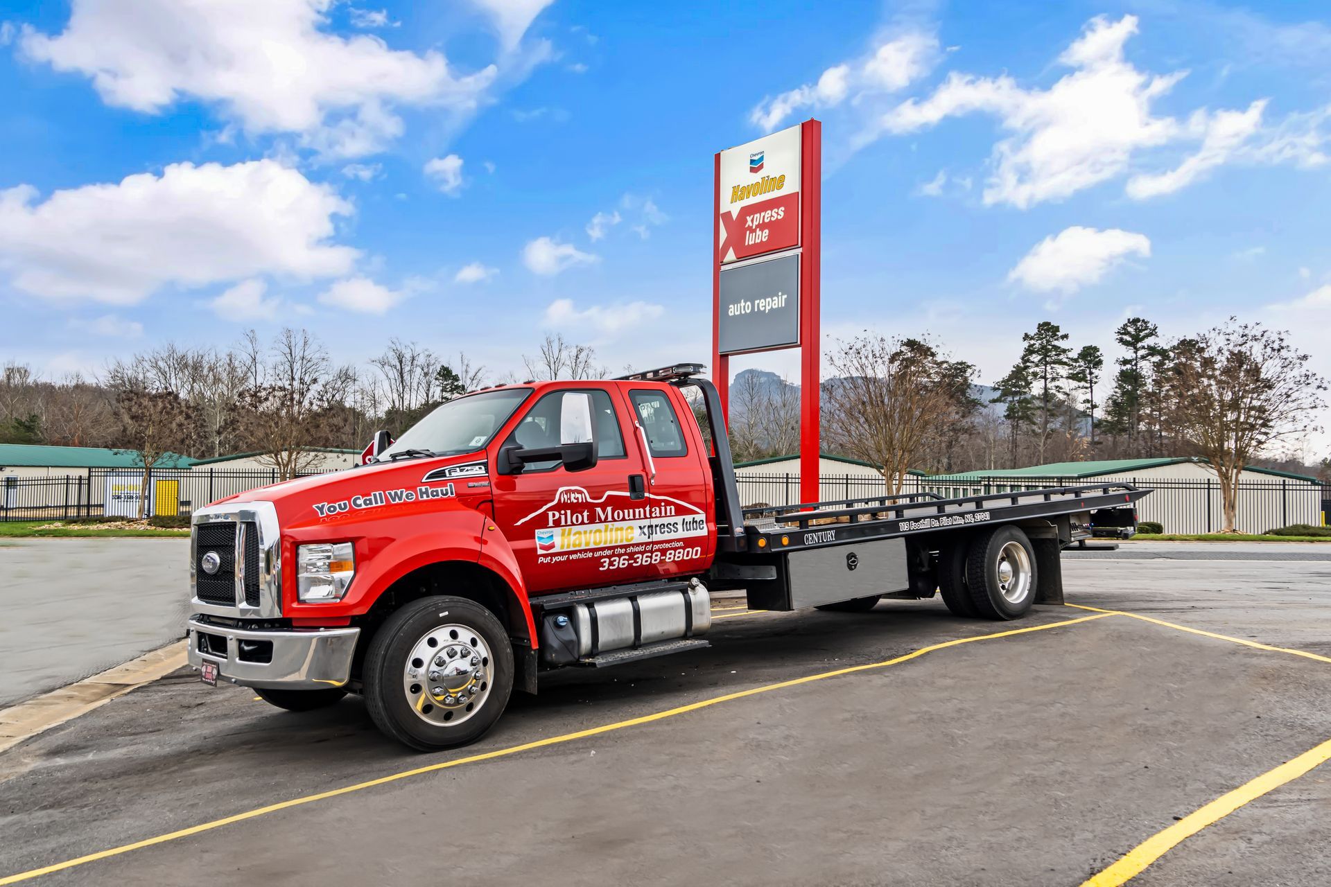 Red flatbed tow truck parked in a lot on a cloudy day