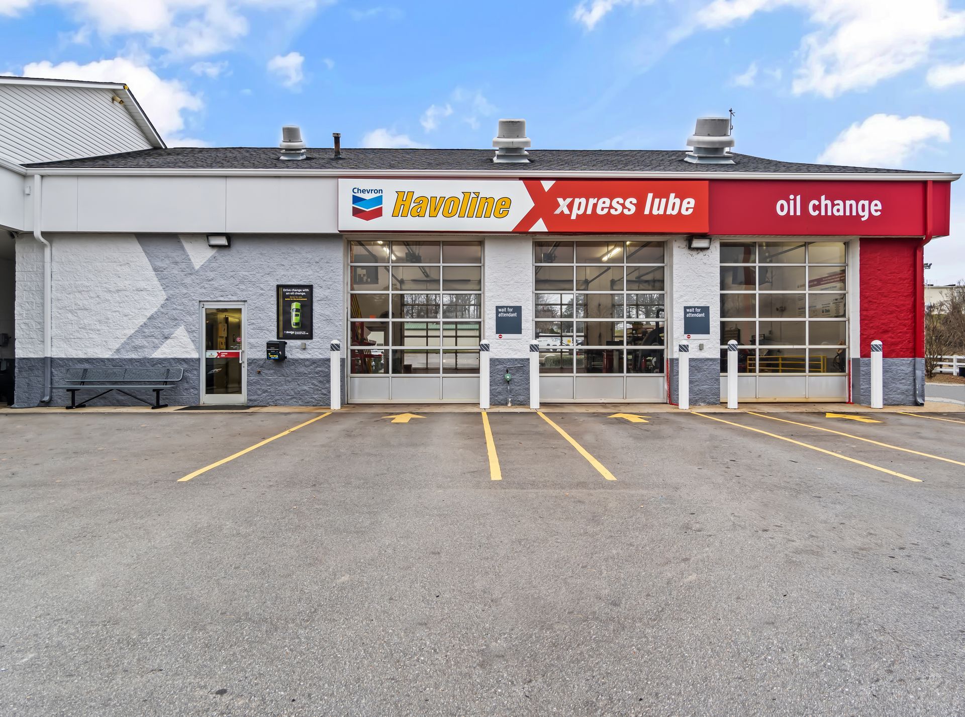 Small grocery and gas station storefront with red signage and empty parking spaces in front