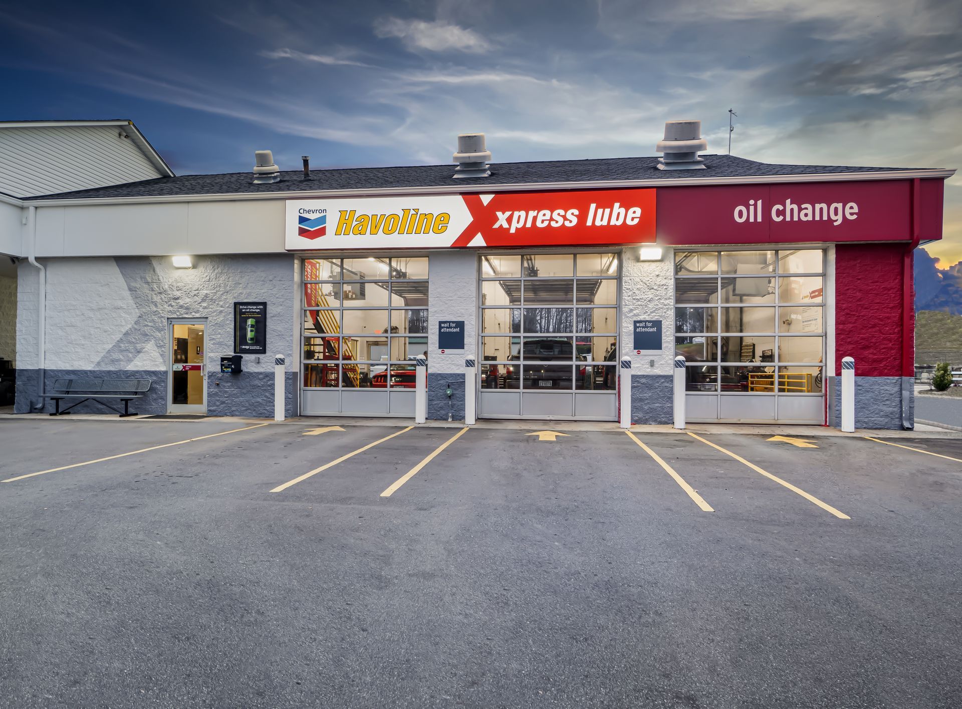 Storefront of an Xpress Lube oil change shop with gray exterior and red signage, seen from the parking lot