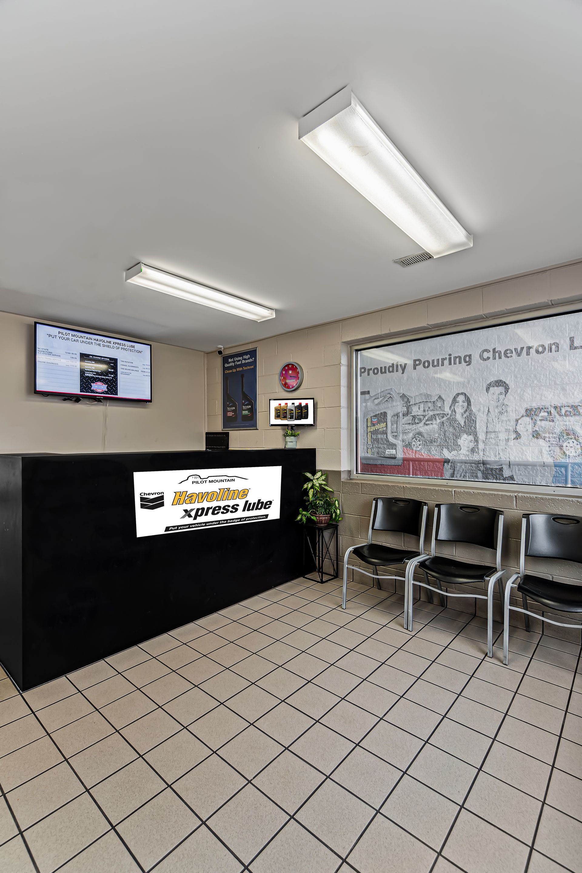 Small office lobby with reception desk, wall TV, chairs, and large hand-drawn sign on the wall.