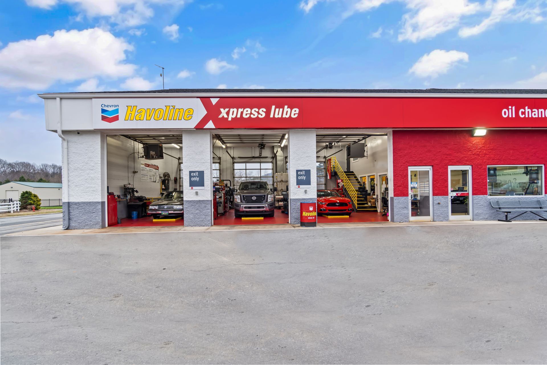 Gas station with red and white Xpress Lube service bays under a blue sky