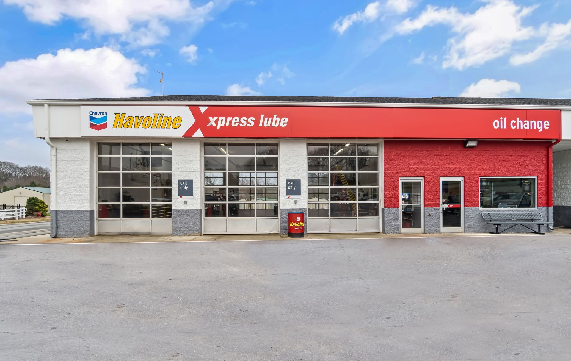 Automotive service shop exterior with red sign, garage doors, and oil change branding