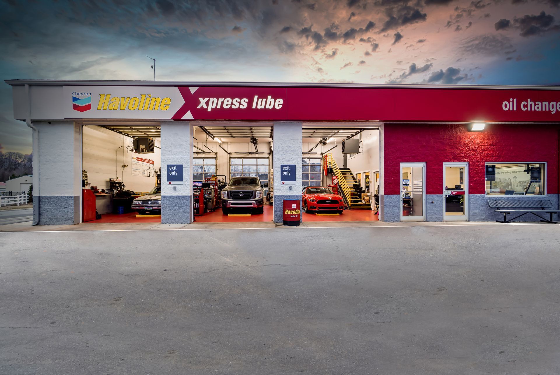 Auto service shop exterior with open bays, red signage, and cars visible inside
