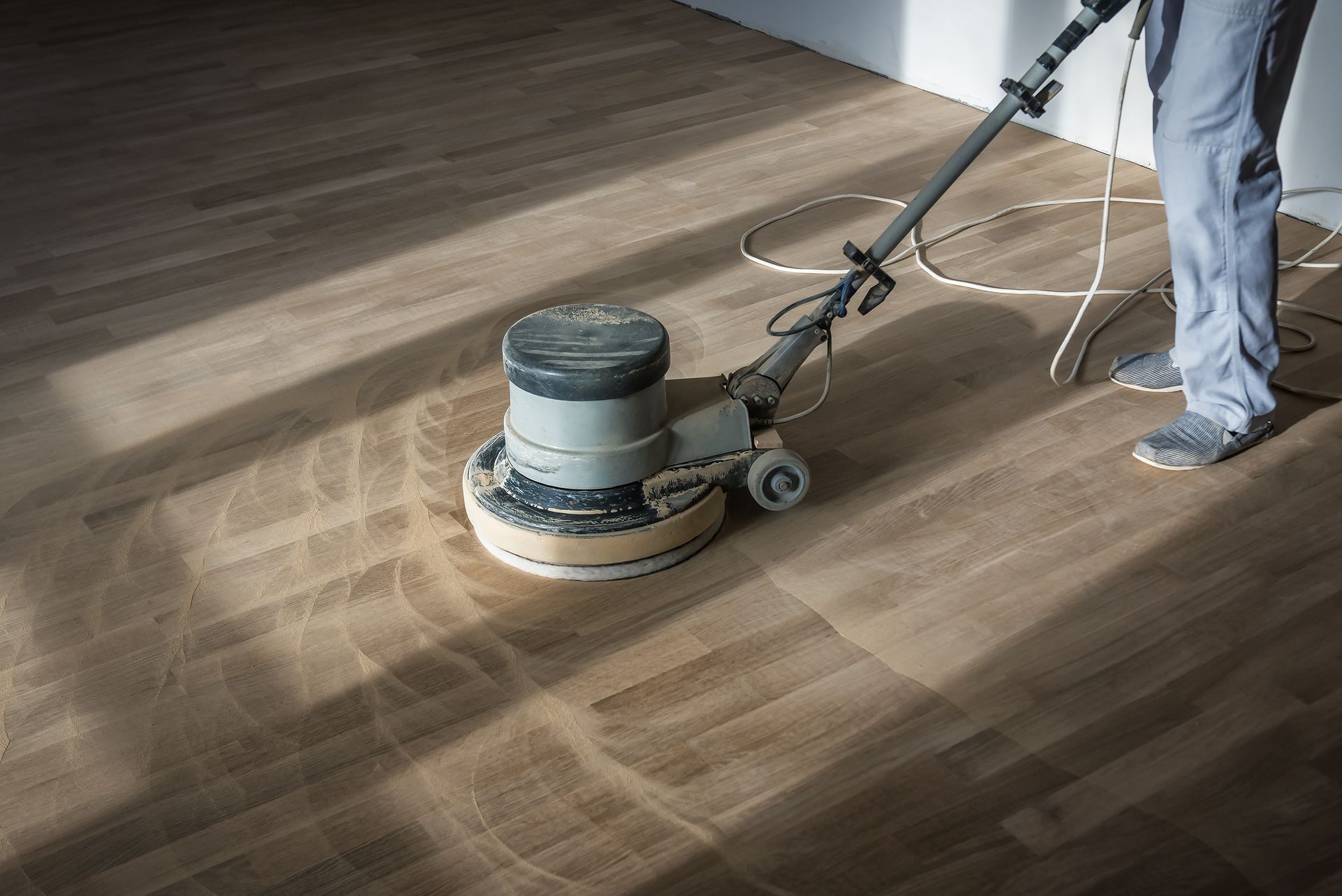 Wood floor polishing machine smoothing a hardwood floor.