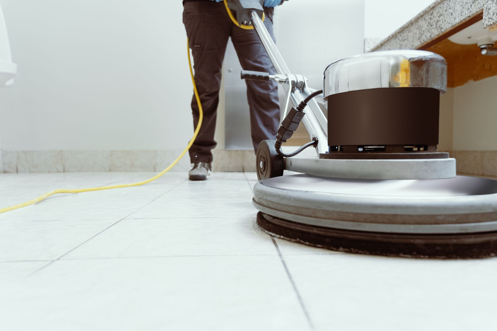 Technician operating a rotary floor buffer on tile flooring