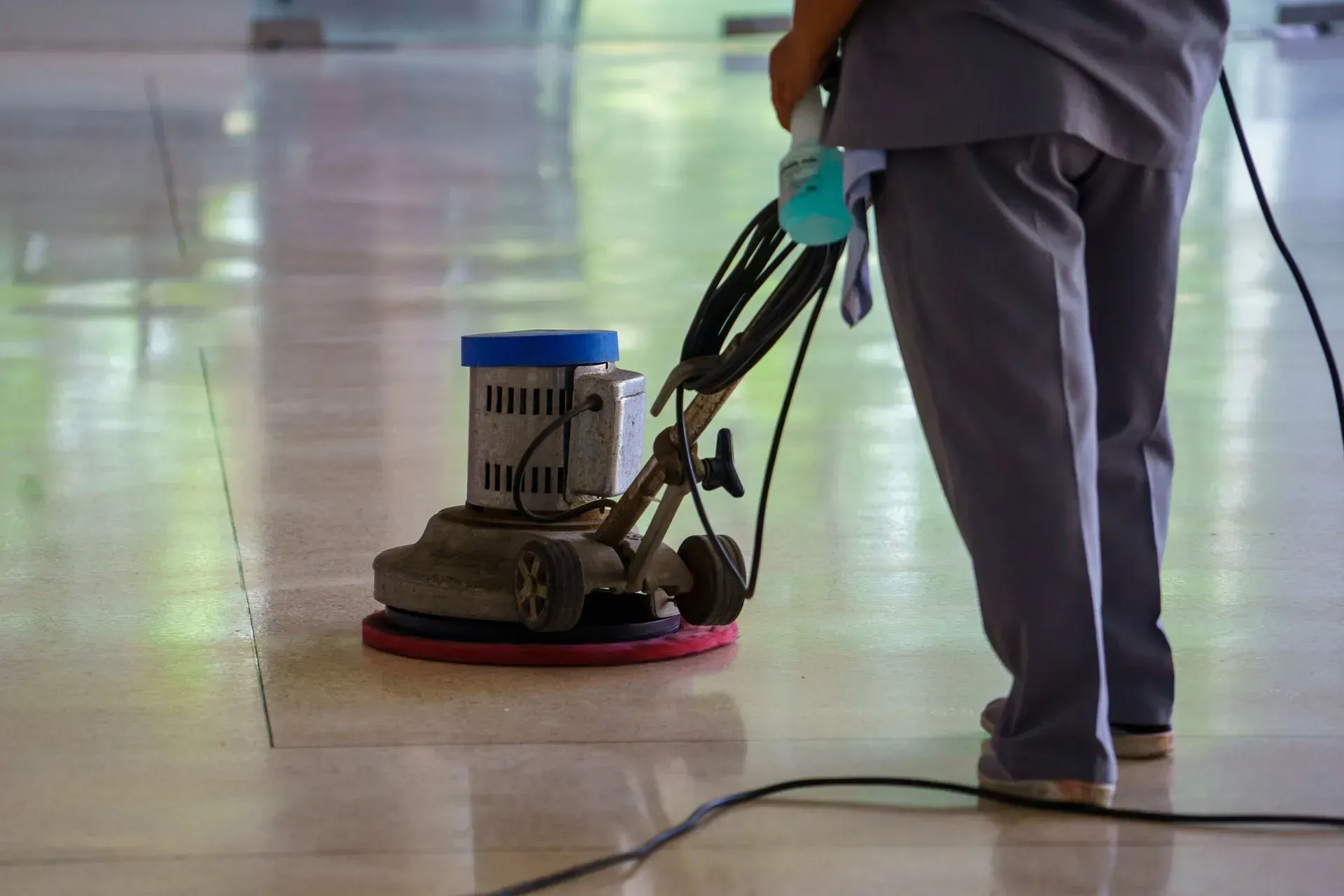 Man operates a vacuum cleaner on a tile floor, showcasing professional cleaning services in action.