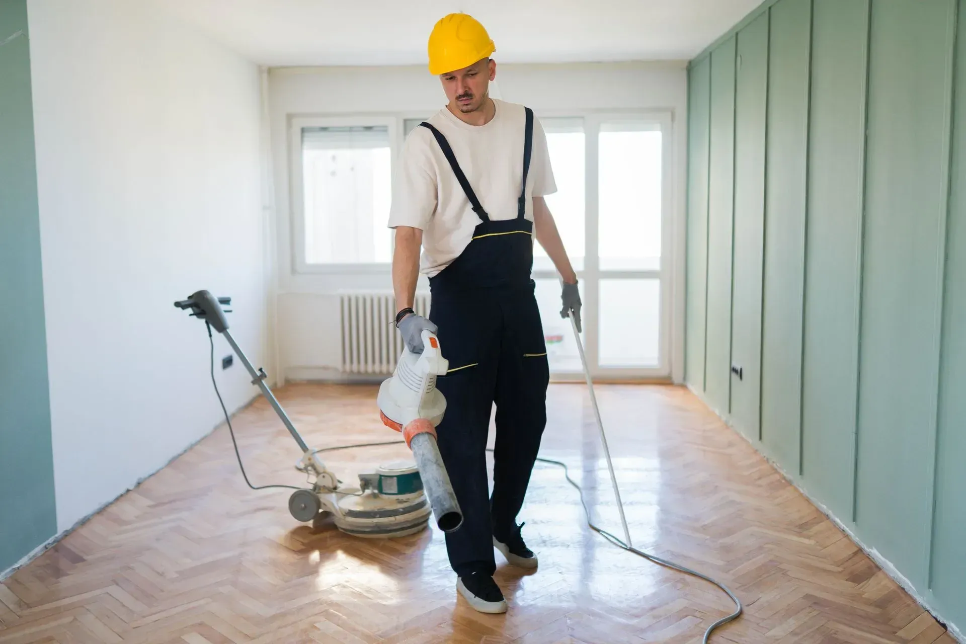 Technician polishing parquet flooring during expert tile floor cleaning services in a living room. Technician polishing parquet flooring during expert tile floor cleaning services in a living room.