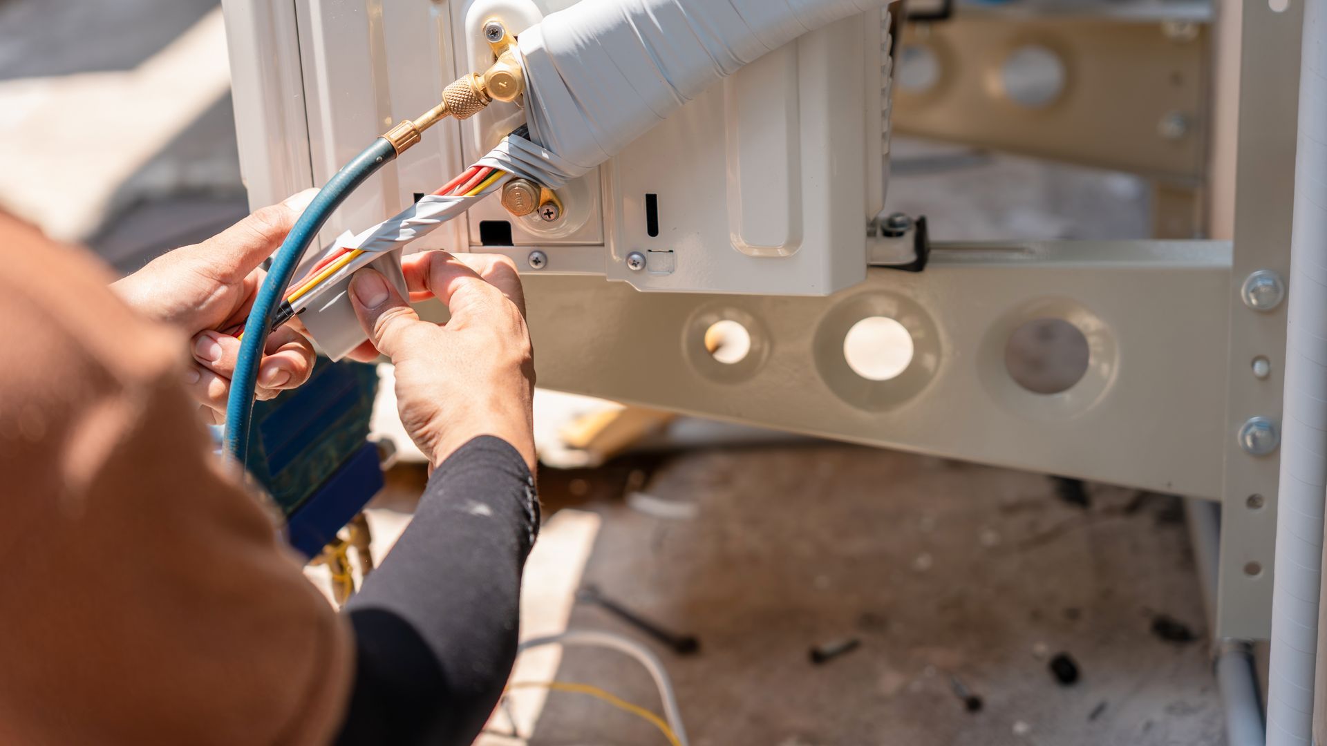 Technician connecting electrical wires to a machine panel with tools in a workshop