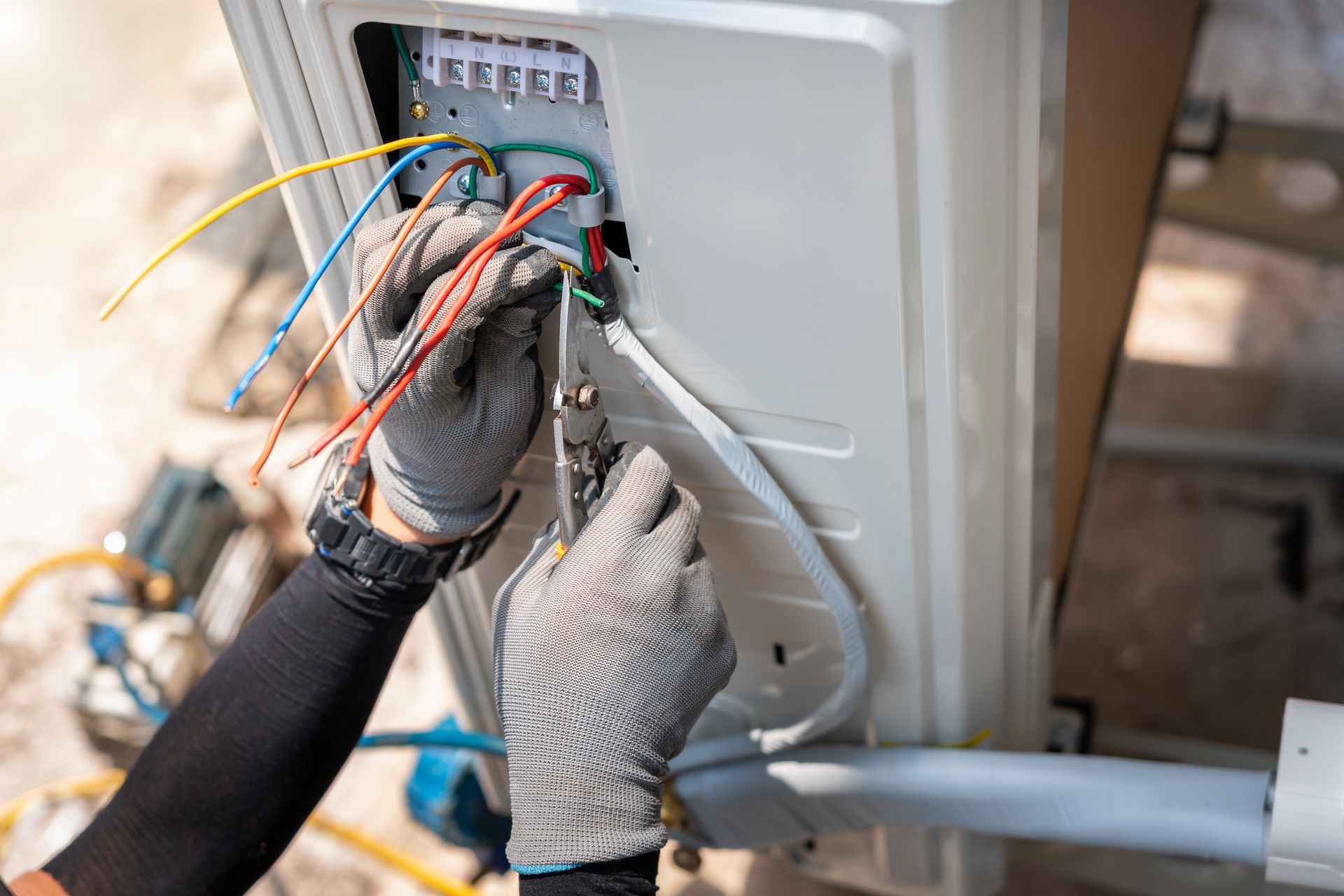 Technician wiring an electrical panel with multicolored cables and gloved hands