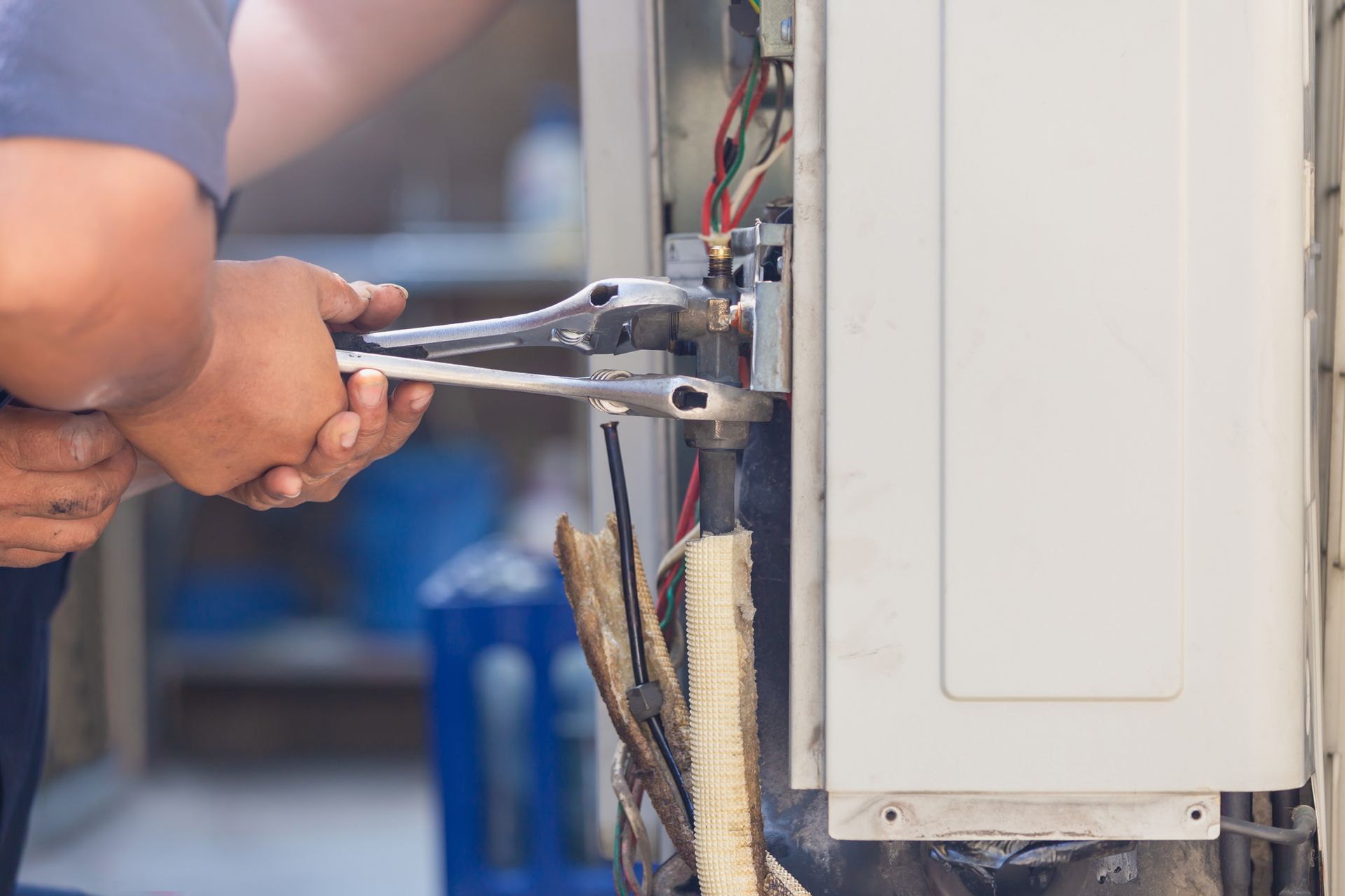 Hands using pliers to repair wiring inside an electrical panel