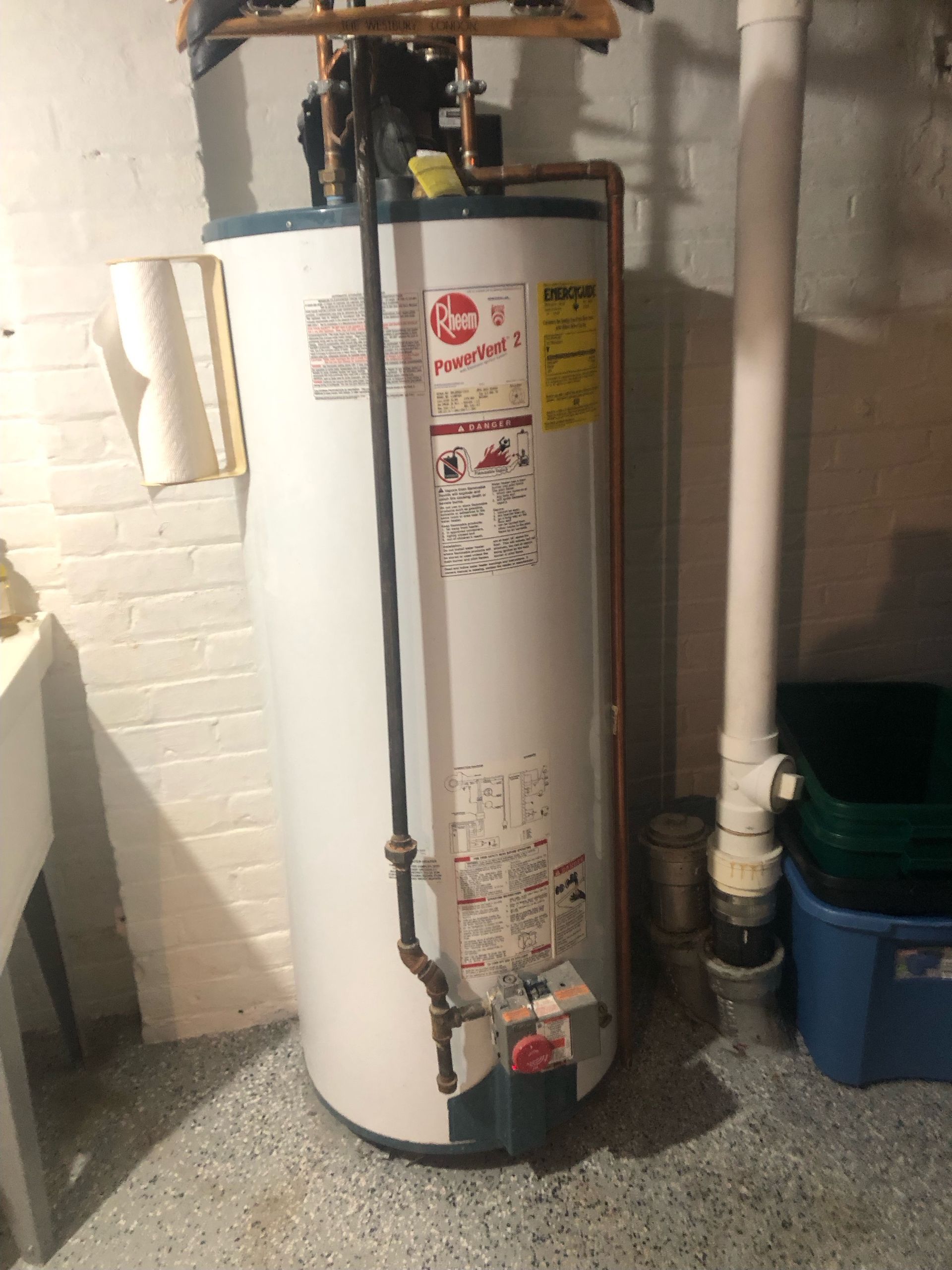 Technician installing a standard tank water heater in a residential basement