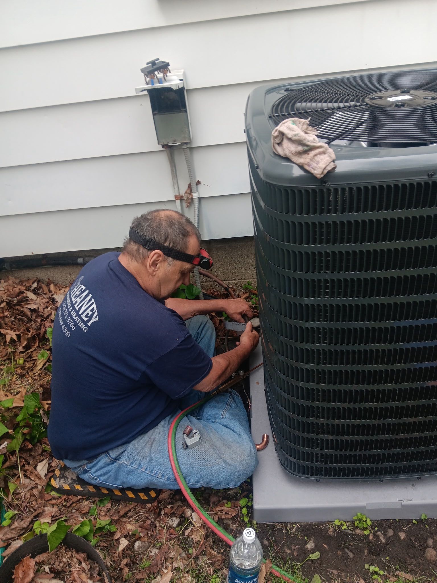 Technician installing a new central air conditioning condenser unit at a Southeast Michigan home.