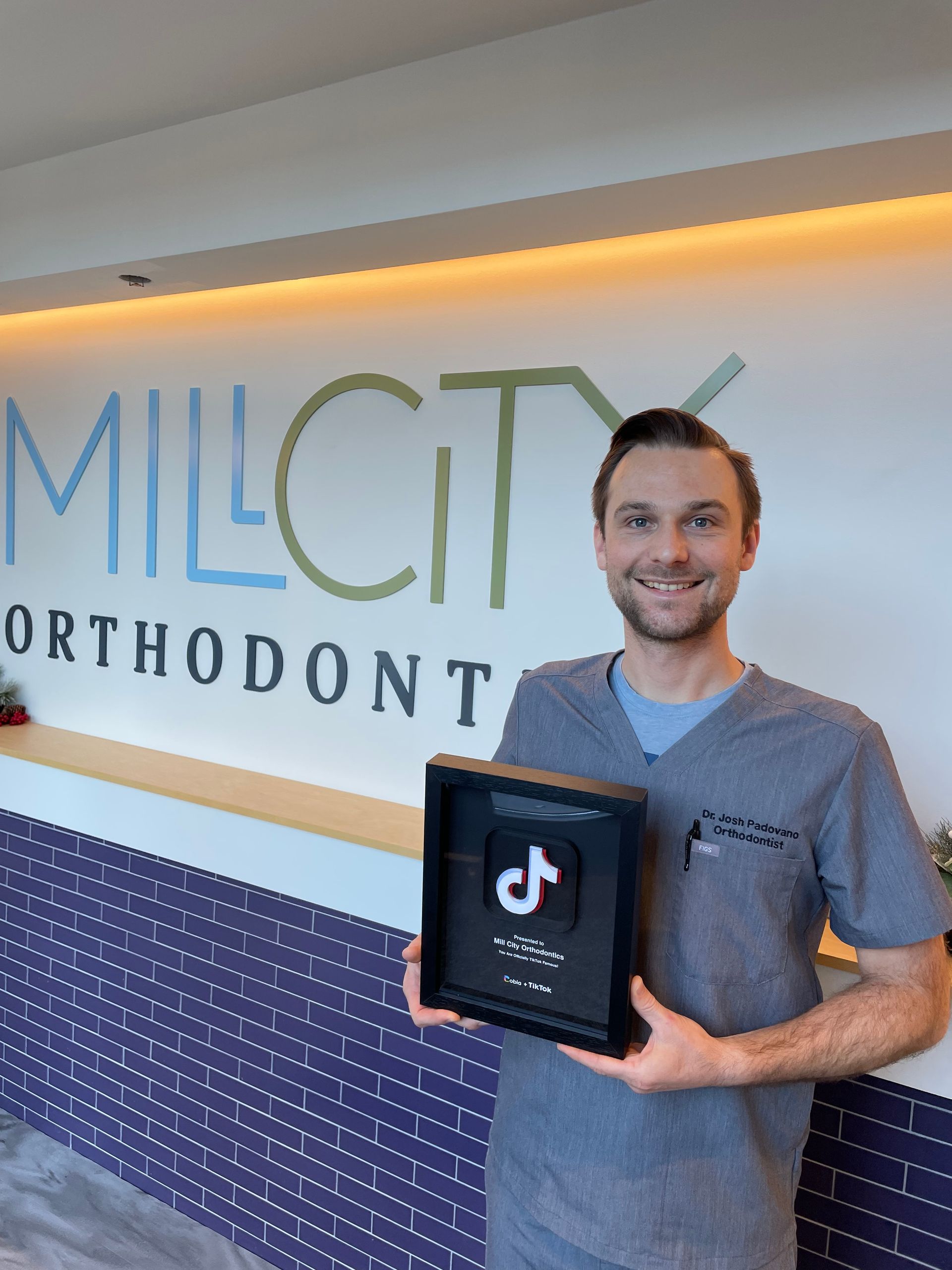 A man in a blue shirt is holding a tik tok plaque