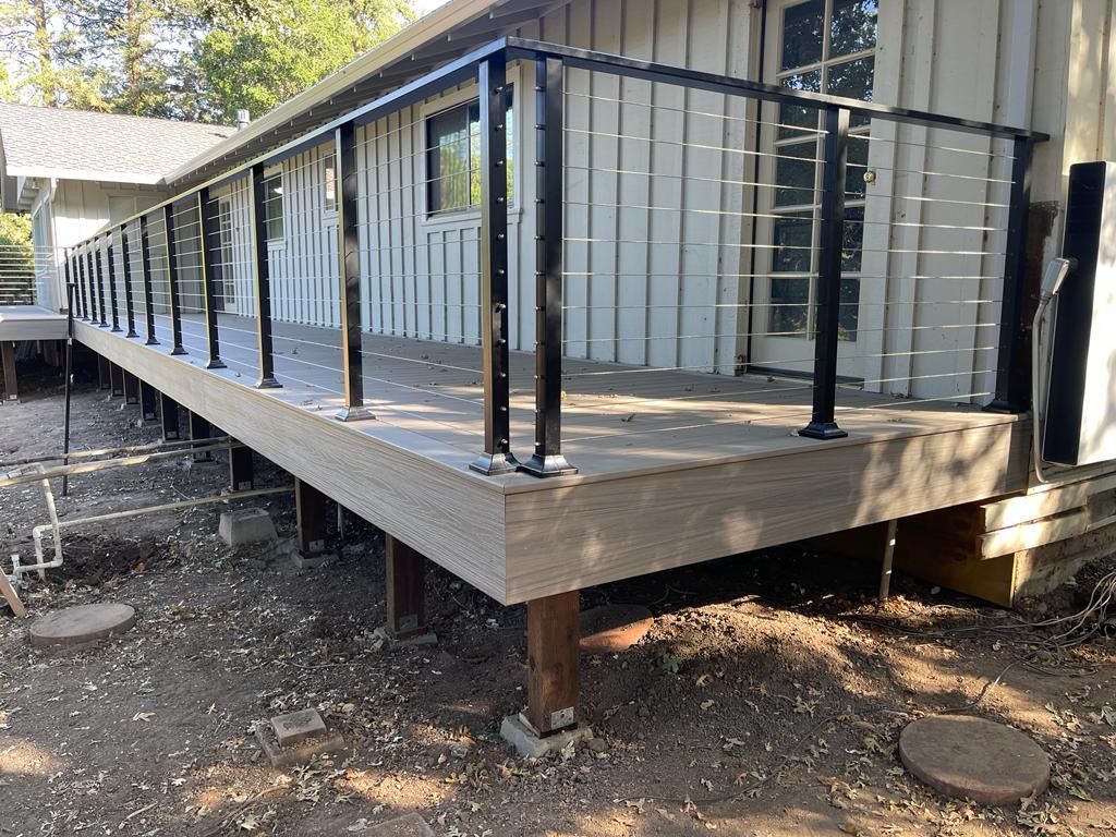 Wooden deck with black railing against a light-colored house.