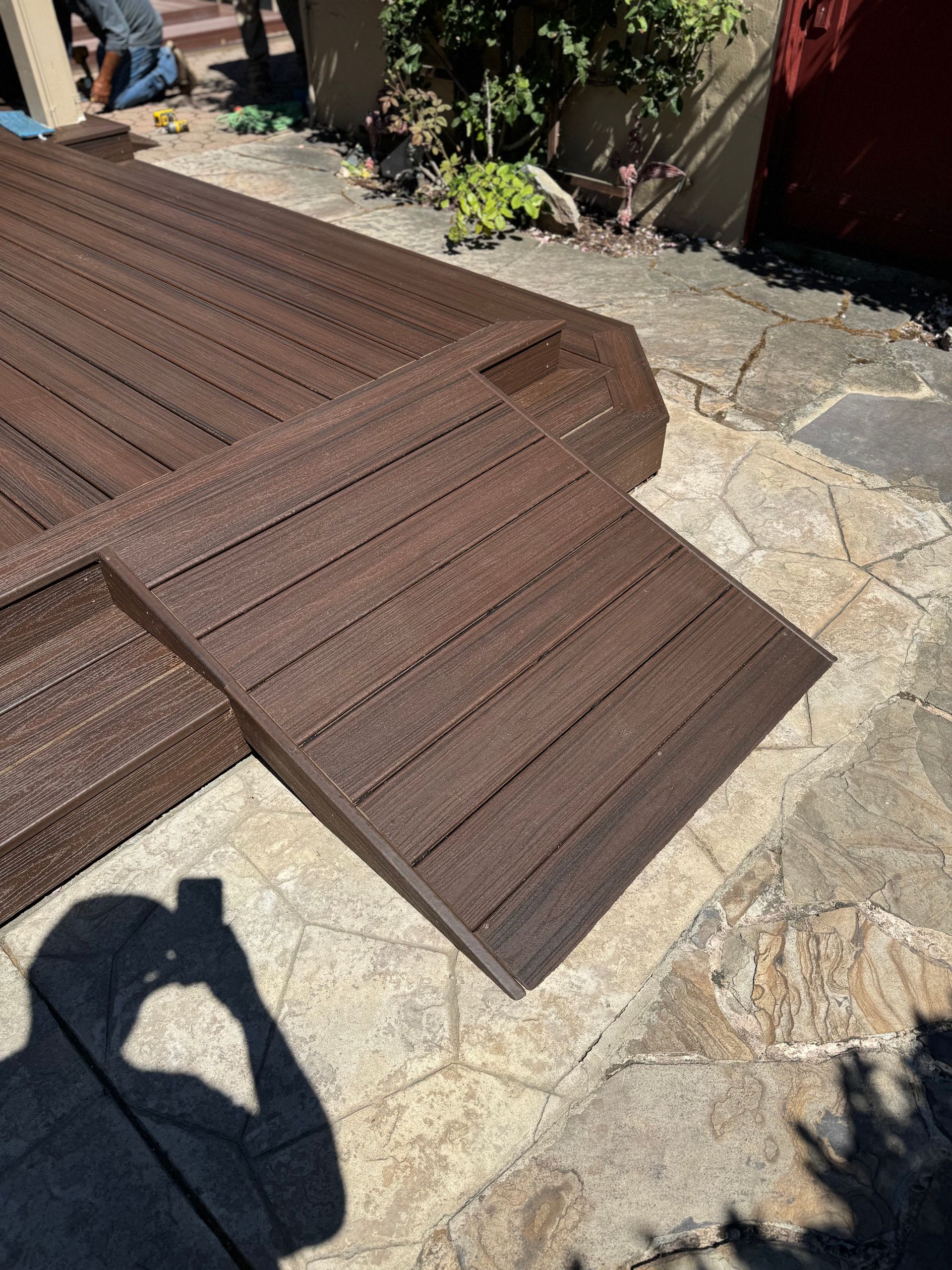 Brown ramp and deck sections on a stone patio, for accessibility.