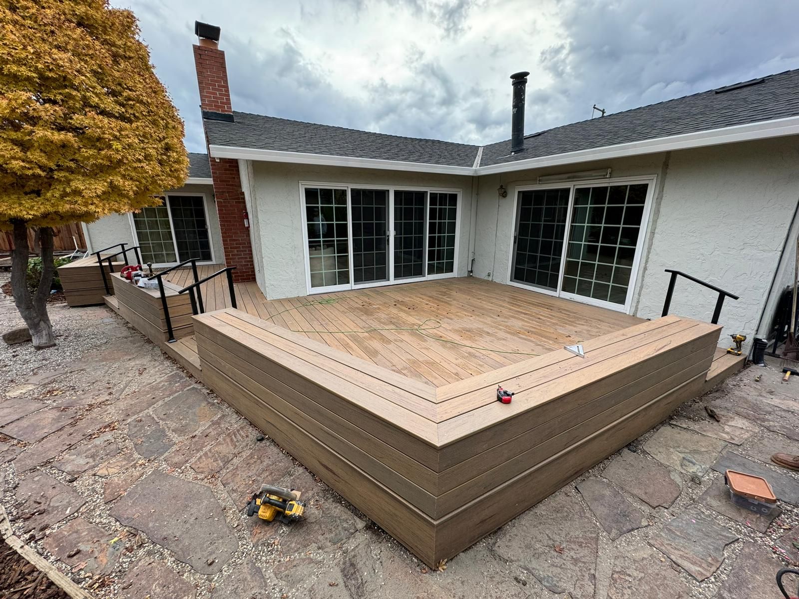 Backyard deck under construction beside a white house, with wood framing and steps