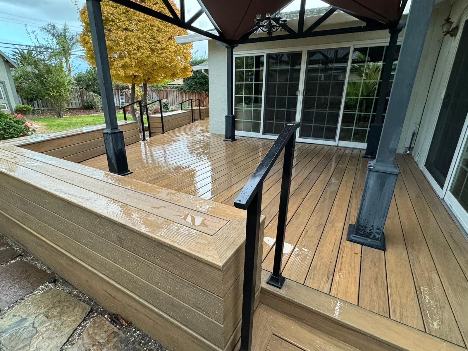 Covered wooden deck with ramp railing and wet floor outside a building