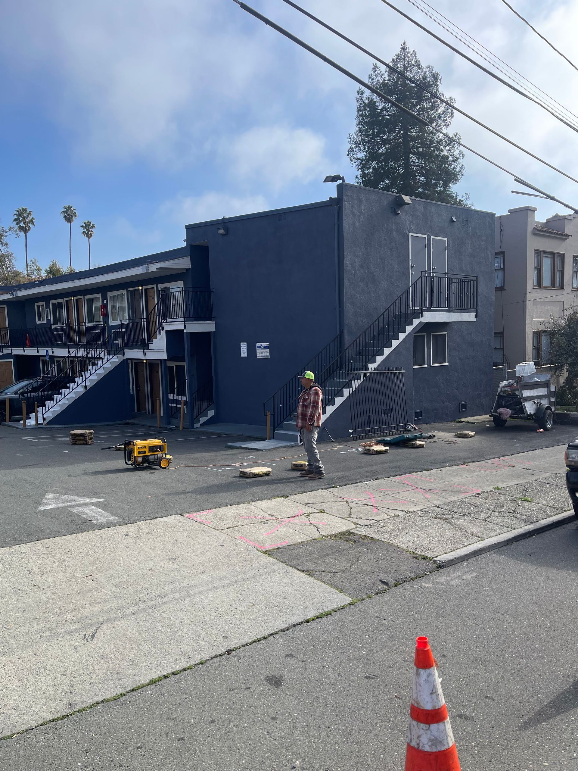 Exterior view of a building under construction, a worker stands nearby.