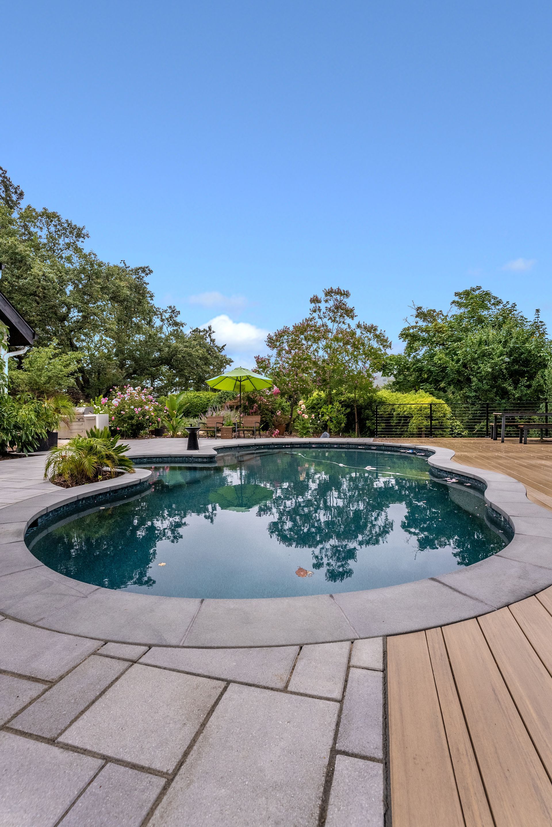 Backyard with a raised house deck, patchy grass, and a swing set on the right.