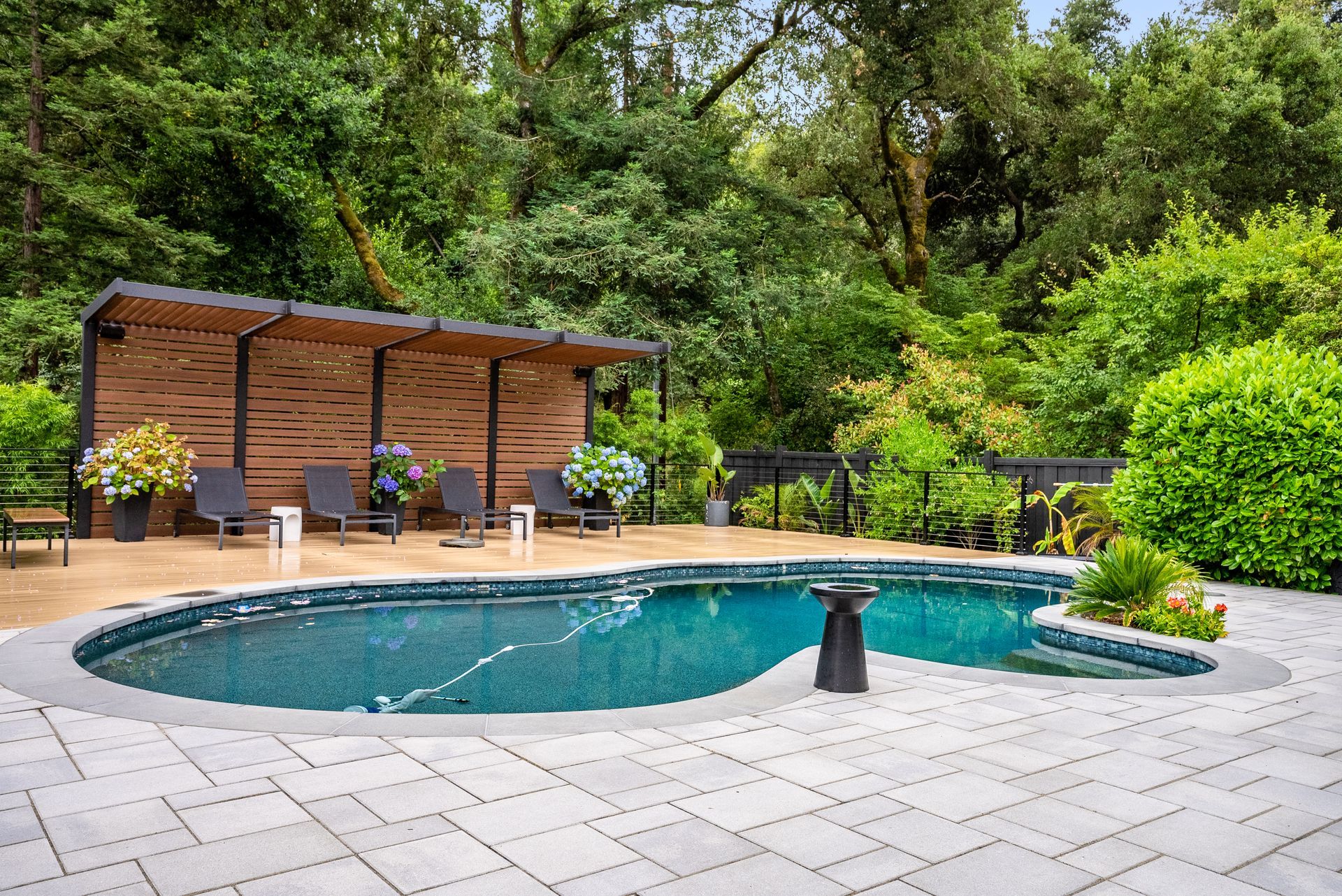 Backyard pool and hot tub beside a wooden cabana in a lush green garden