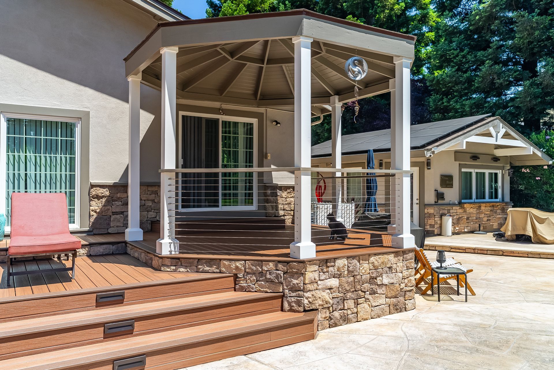 Backyard patio with covered deck, brick steps, and outdoor seating beside a house