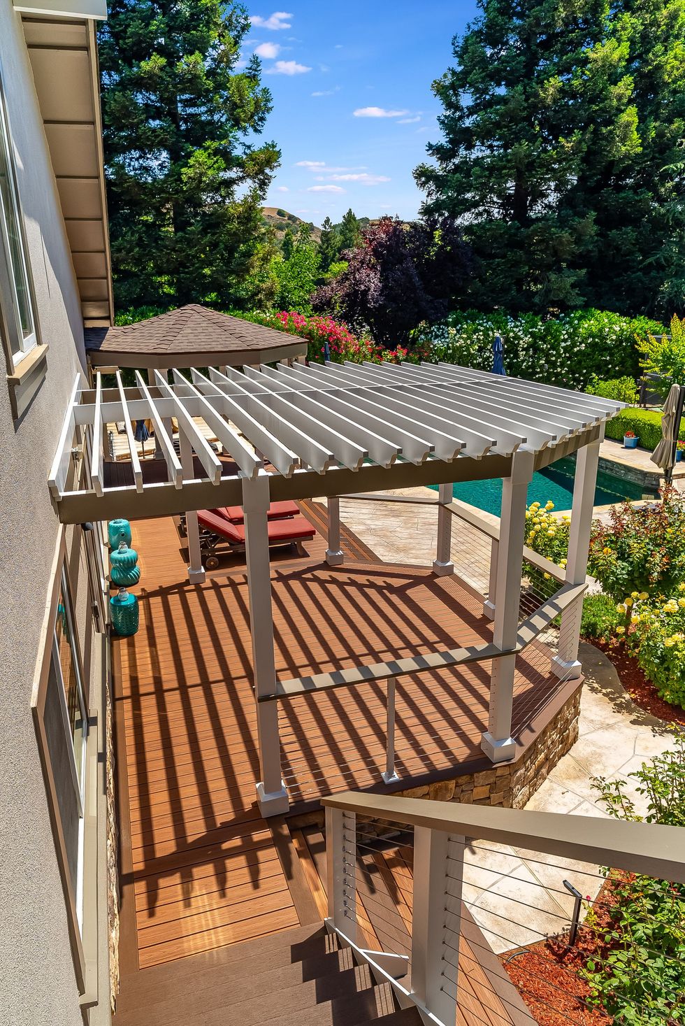 Backyard patio with a white pergola, brick steps, and lush green garden views