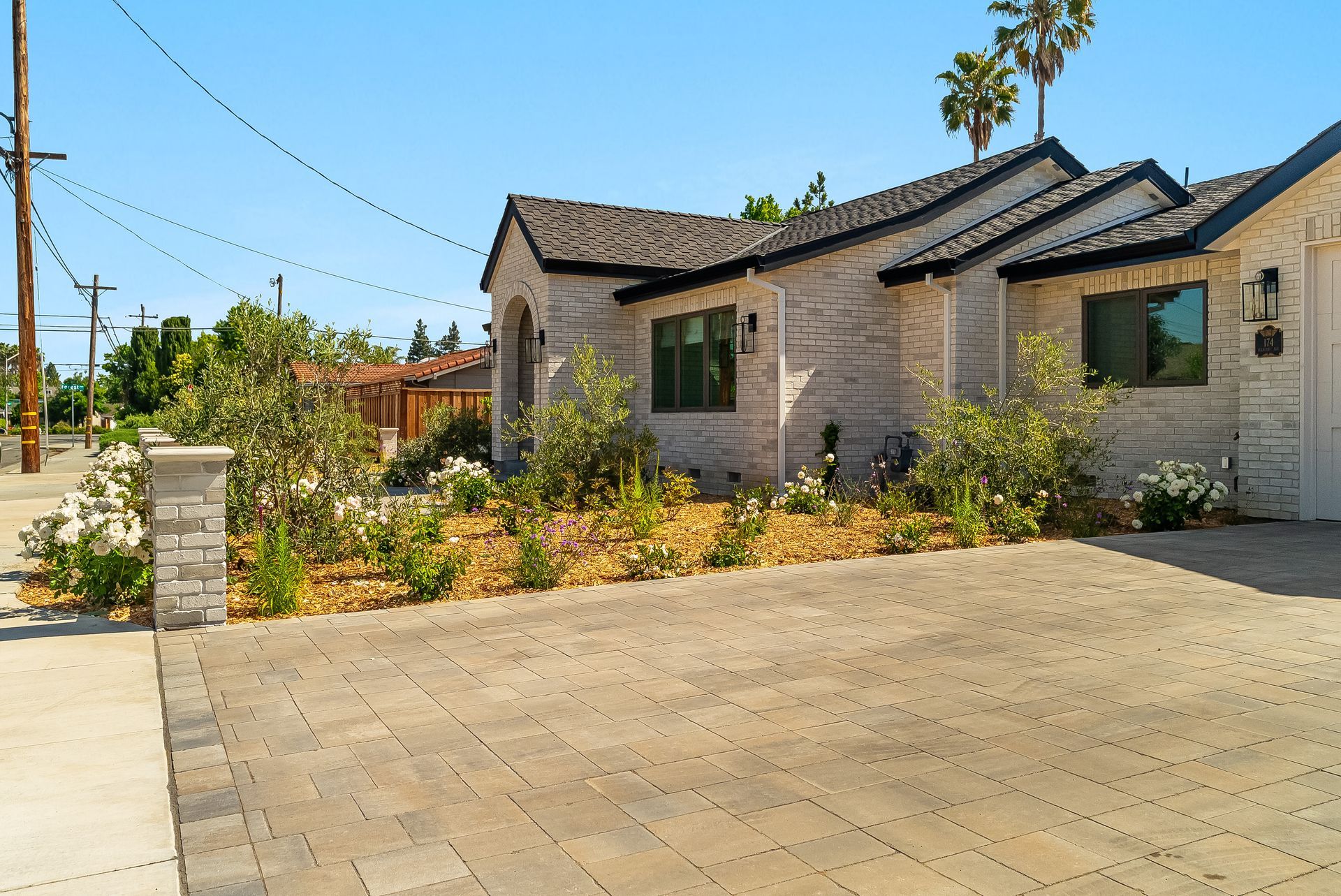 Sunny suburban house with stone facade, driveway, palm trees, and desert landscaping