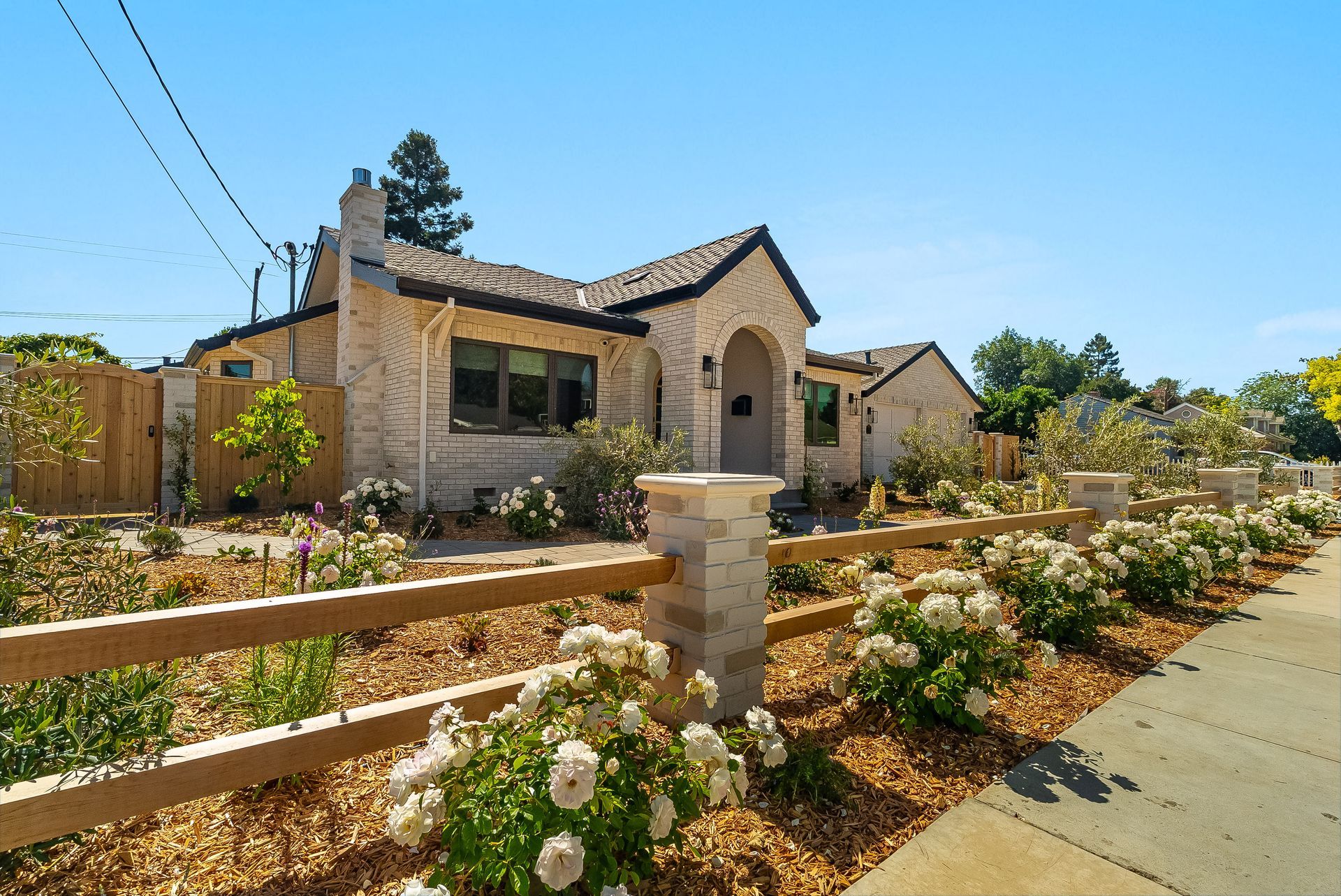 Stone house with a flower garden and wooden fence in bright sunlight