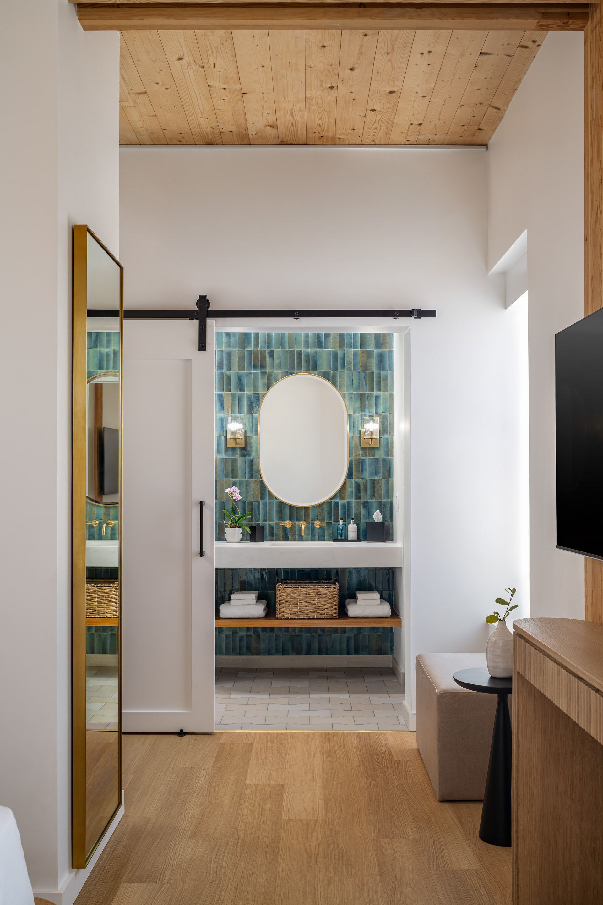 Modern bathroom with glass shower, toilet, stone sink, green accent wall, and gold fixtures.