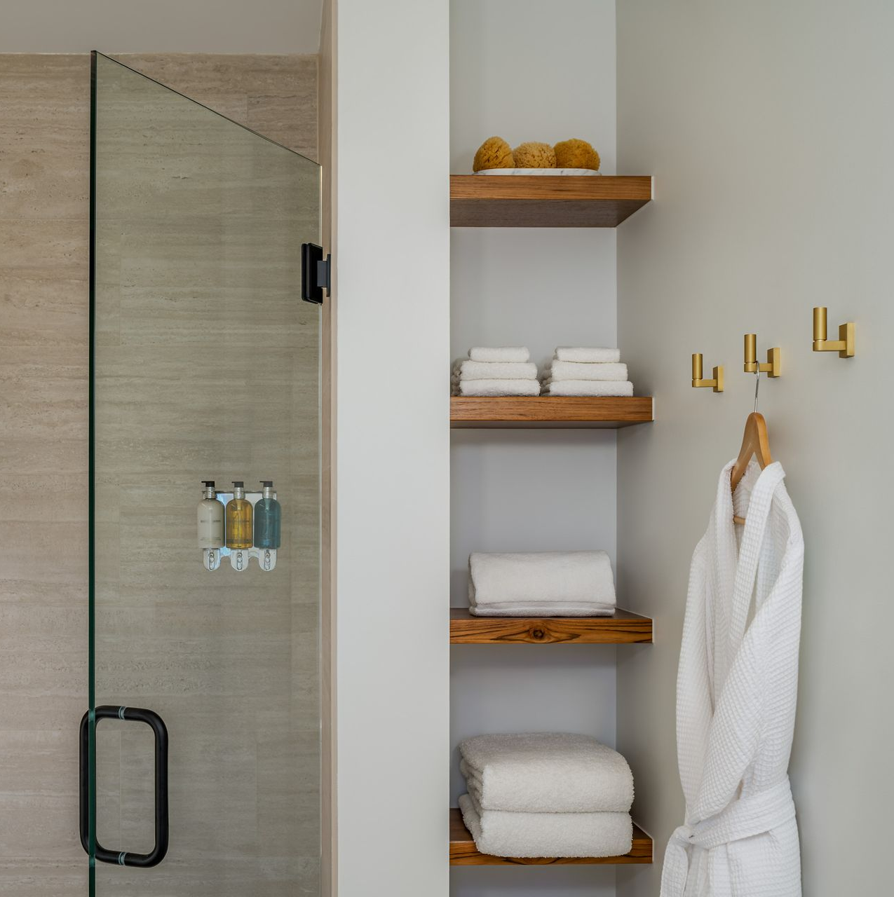 Modern bathroom with glass shower, toilet, floating sink, green tile accent, and gold fixtures.