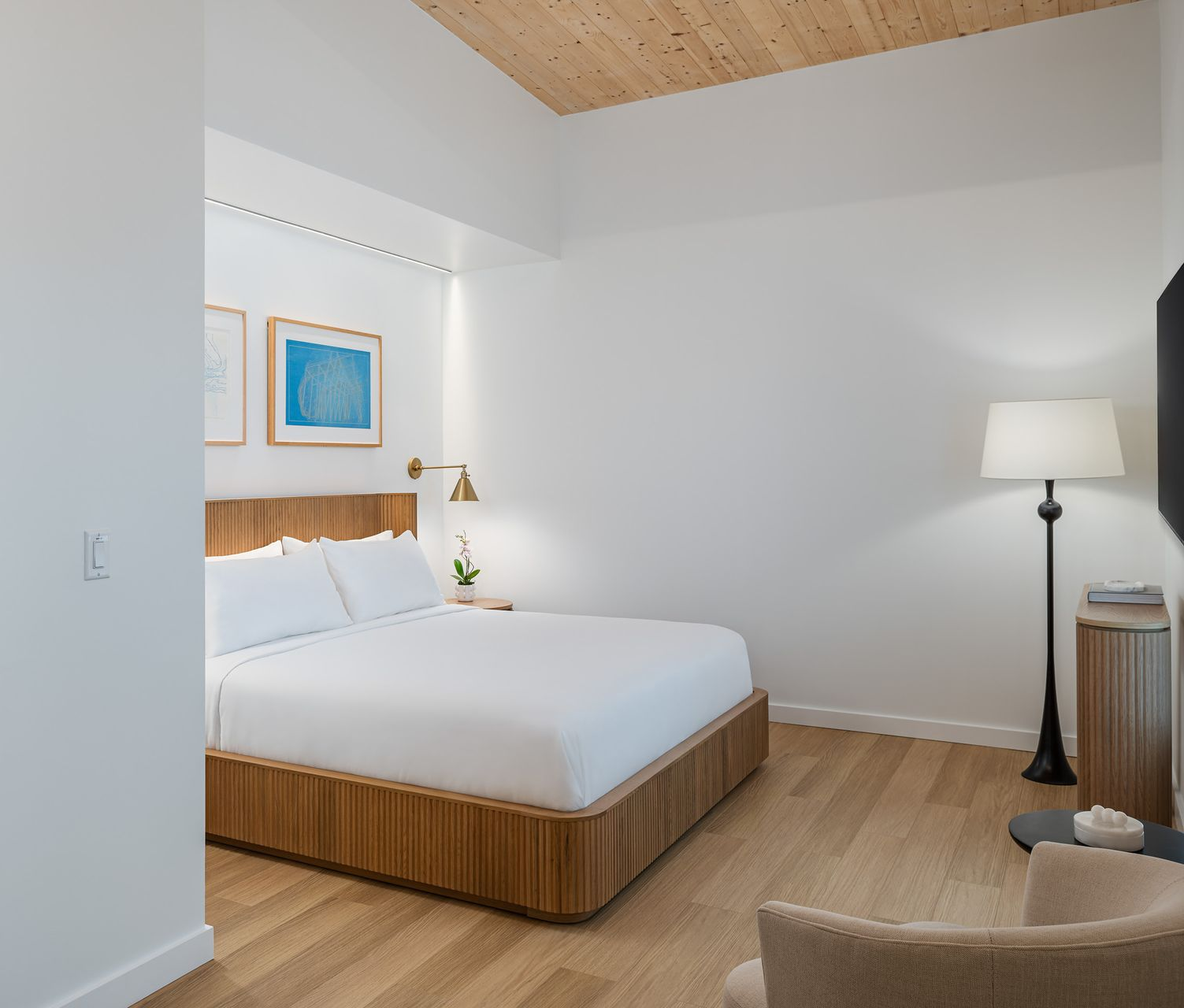 Bedroom with wooden accents, sliding glass door to bathroom, beige and warm lighting.