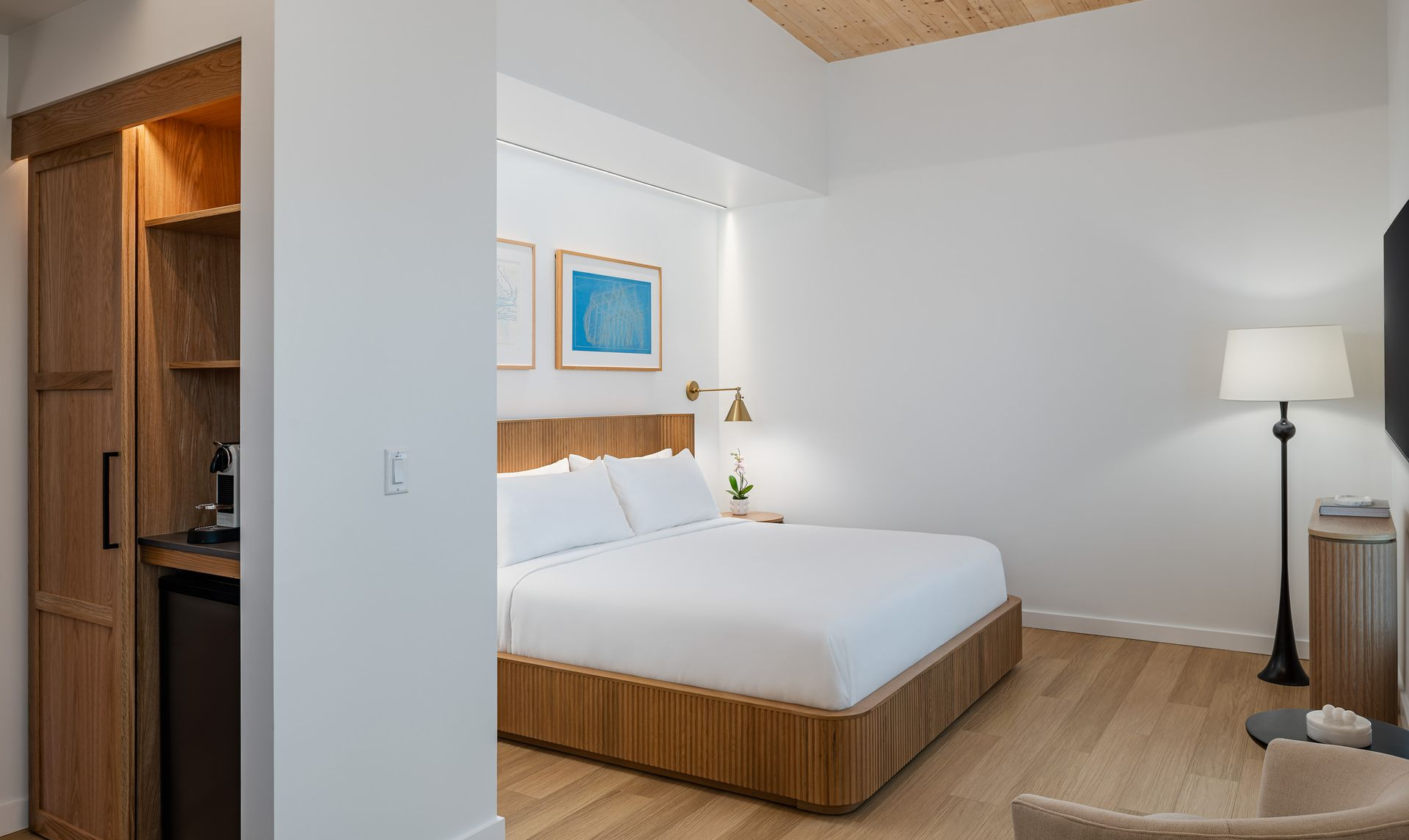 Cozy bedroom with wooden bed, woven chairs, and bathroom visible through a sliding door.