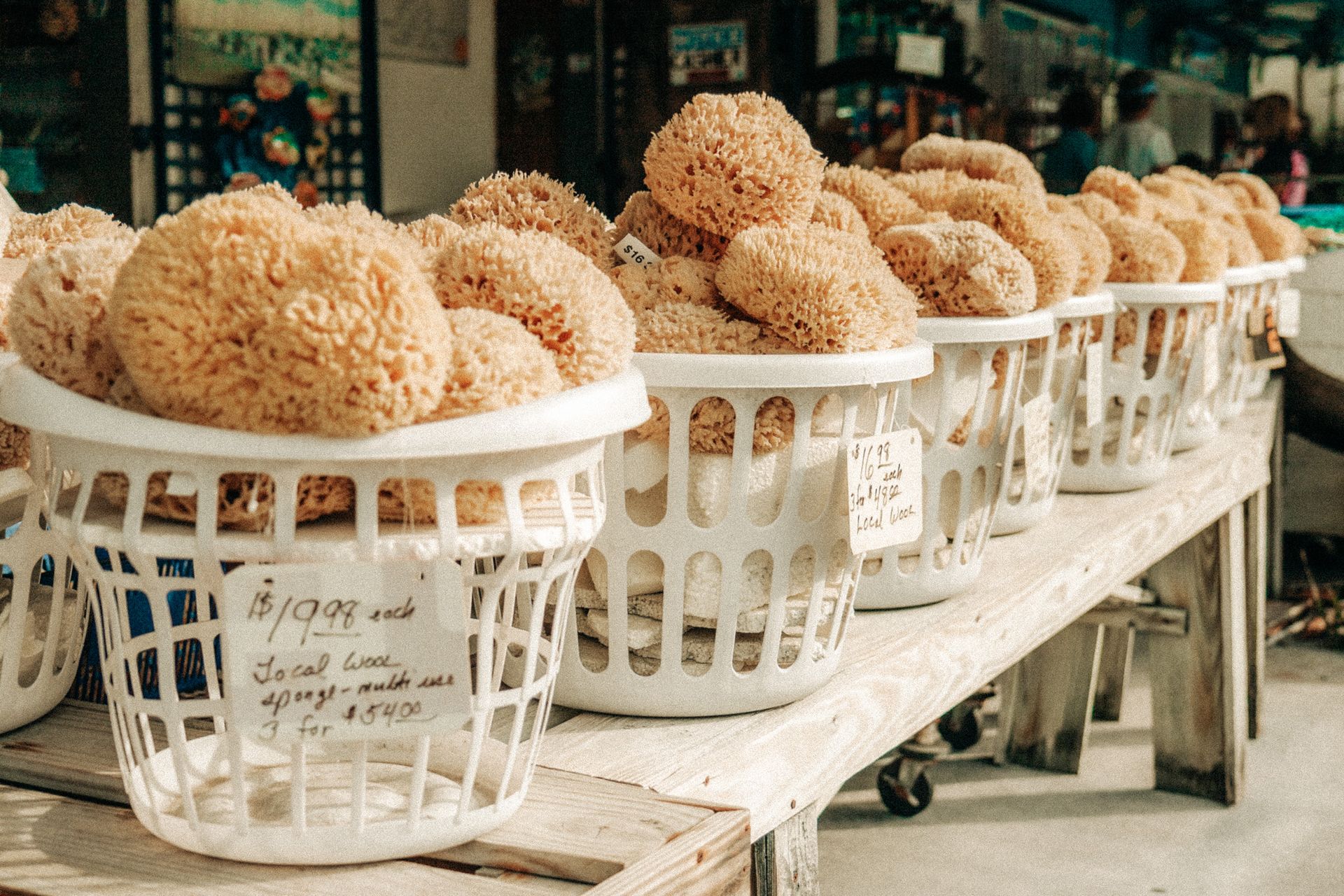 Baskets filled with natural sea sponges for sale on a wooden table.