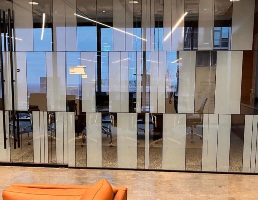 A room with a couch and a chair in front of a glass wall.