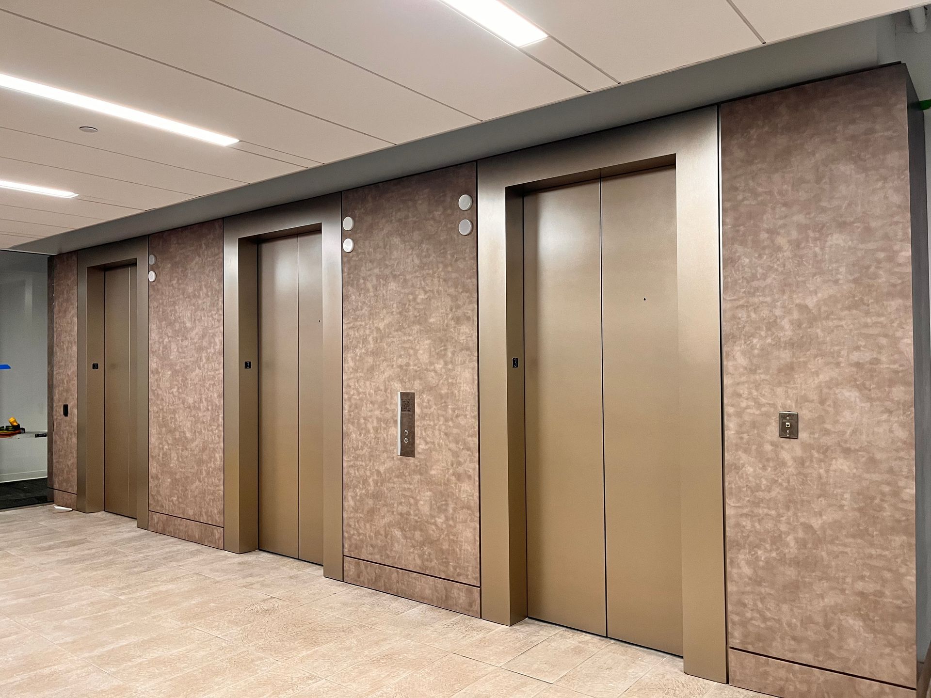 A row of elevators are lined up in a building under construction.