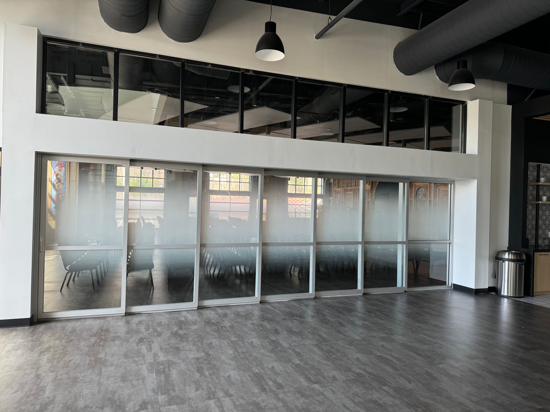 Empty modern office lobby with glass partition doors and gray wood flooring