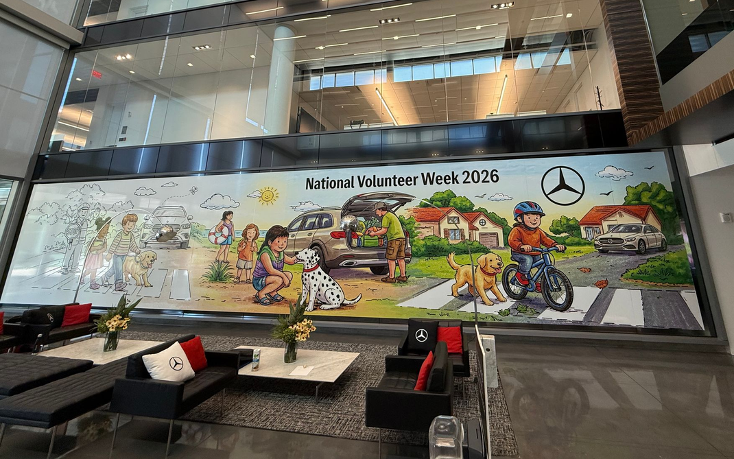 Large colorful Mercedes-Benz mural in a modern lobby with a black sofa in front