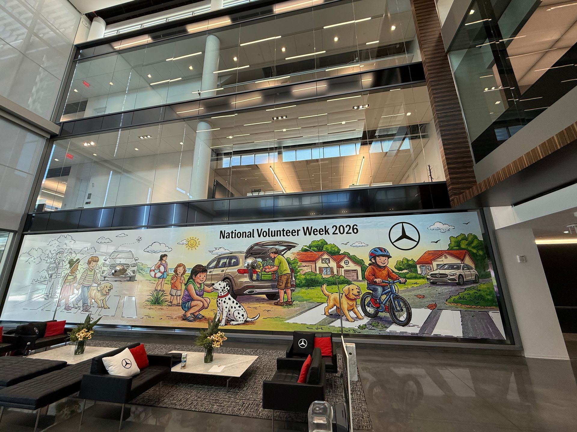 Atrium with Mercedes-Benz Week 2016 mural, cyclists and cars, viewed from a modern lobby