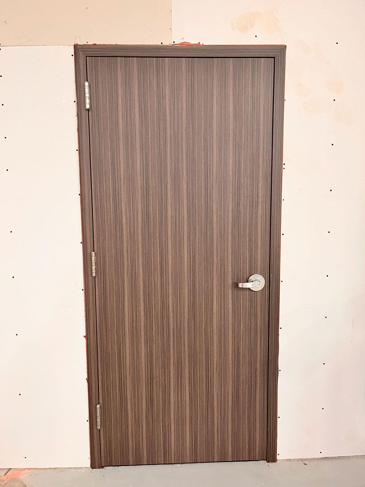 A wooden door is sitting in a room next to a wall.