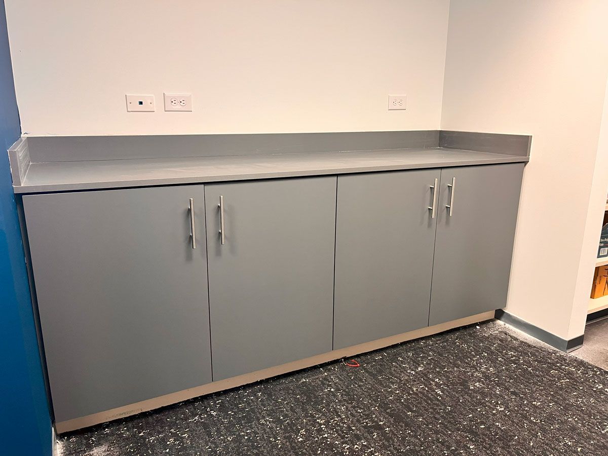 A kitchen counter with gray cabinets and a counter top.