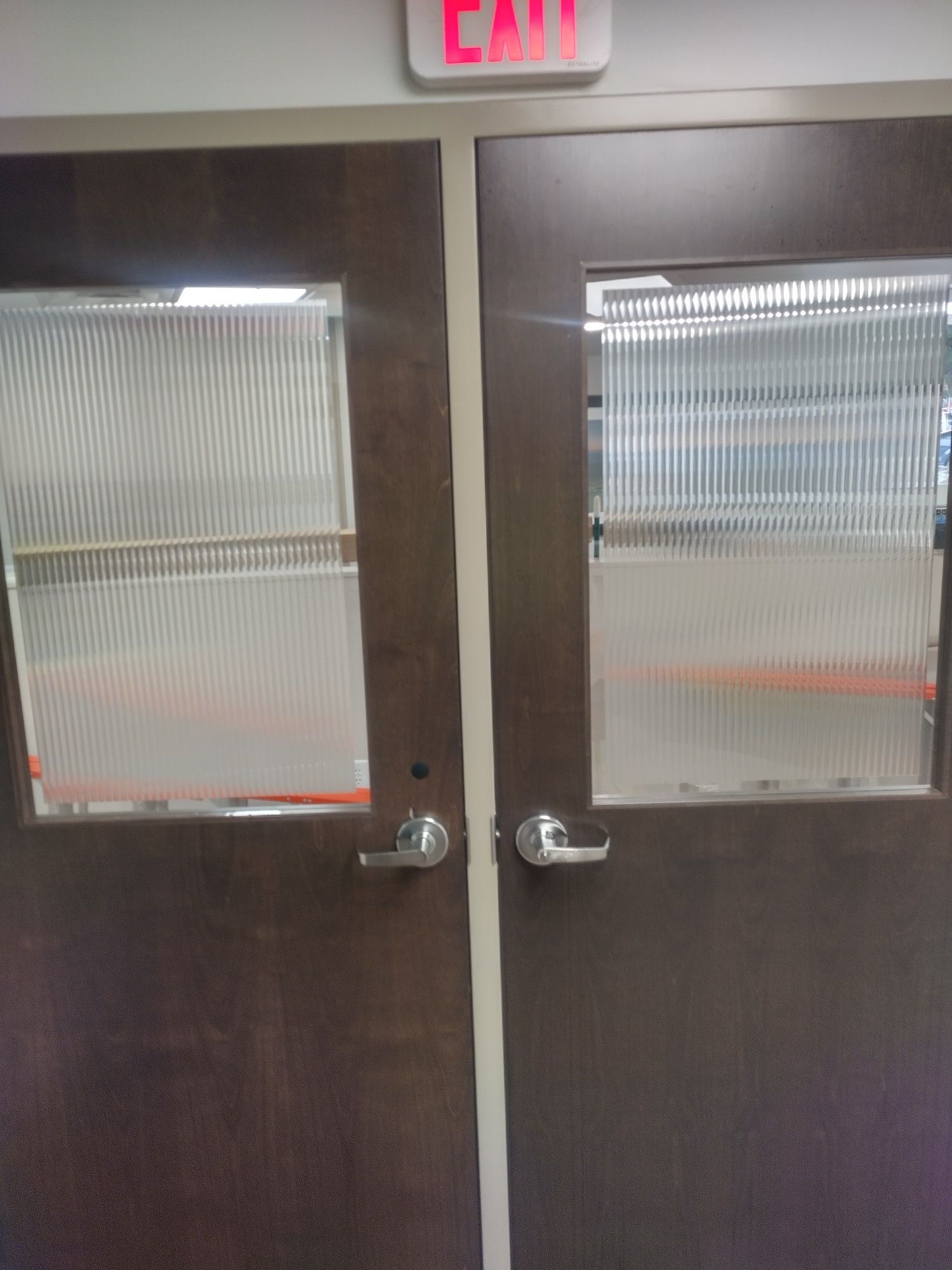 Closed double doors with frosted glass panes and a red EXIT sign above them.