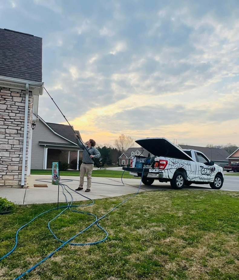Person standing in driveway beside white SUV with open hood and a house in the background