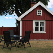 Red wooden house with white trim and patio table with chairs on the lawn