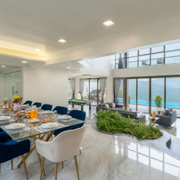 Modern dining room with set table, blue chairs, indoor plants, and large windows overlooking a pool