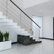 Modern white interior staircase with black handrail, polished tile floor, and potted plant