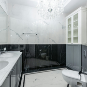 Elegant black-and-white bathroom with marble tile, chandelier, vanity, bathtub, and toilet