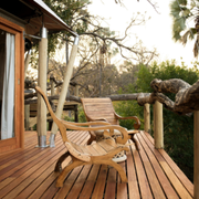 Wooden deck with a lounge chair and small table overlooking trees in a natural setting