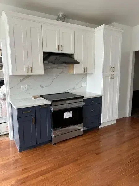 White kitchen with navy lower cabinets, black stove, and hardwood floors